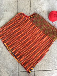 Double-faced panels assembled to form body of poncho with stitches on hand needle for cowl neck