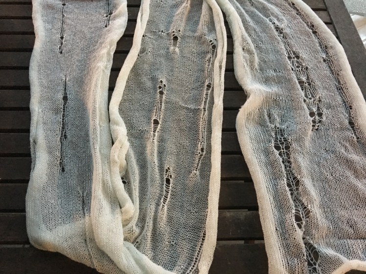 Machine-knit scarf with intentional holes and ladders, before dyeing and felting