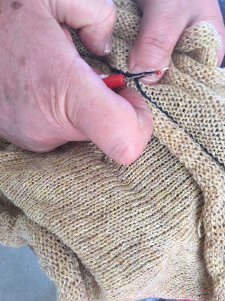 Unraveling waste yarn from machine-knit seam