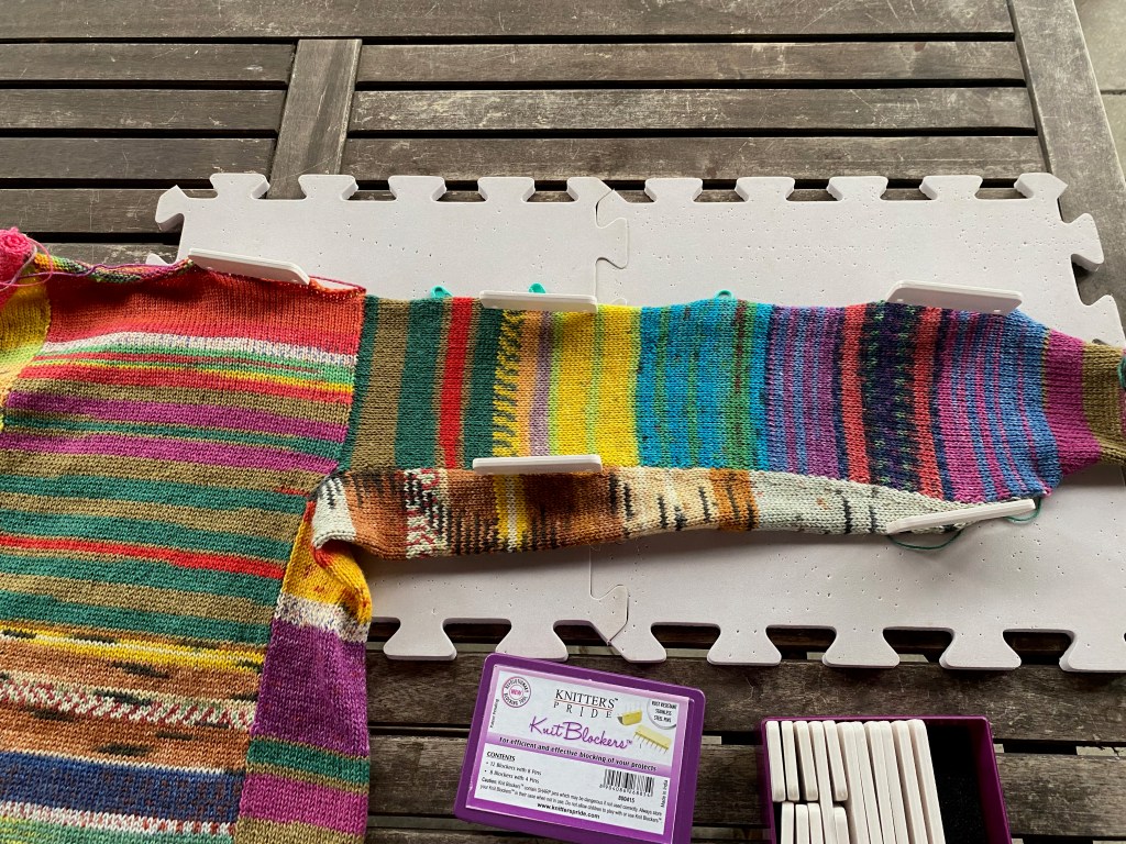 The first of the remaining two sleeve panels has been picked up from the edge of the body and joined to the triangular strip that shapes the sleeve from the bottom side of the arm