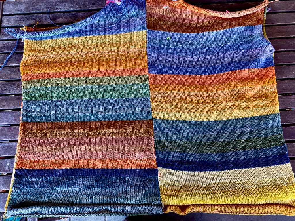 Back of paneled garment with alternating color blocks of green/blue and yellow/orange in offset arrangement