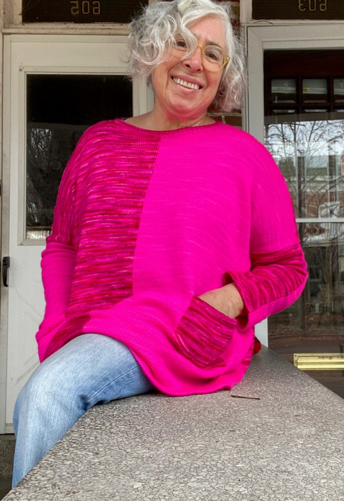 Paneled oversized machine-knit pullover knit in contrasting pink yarns with patch pocket of opposite colors on either side of the front