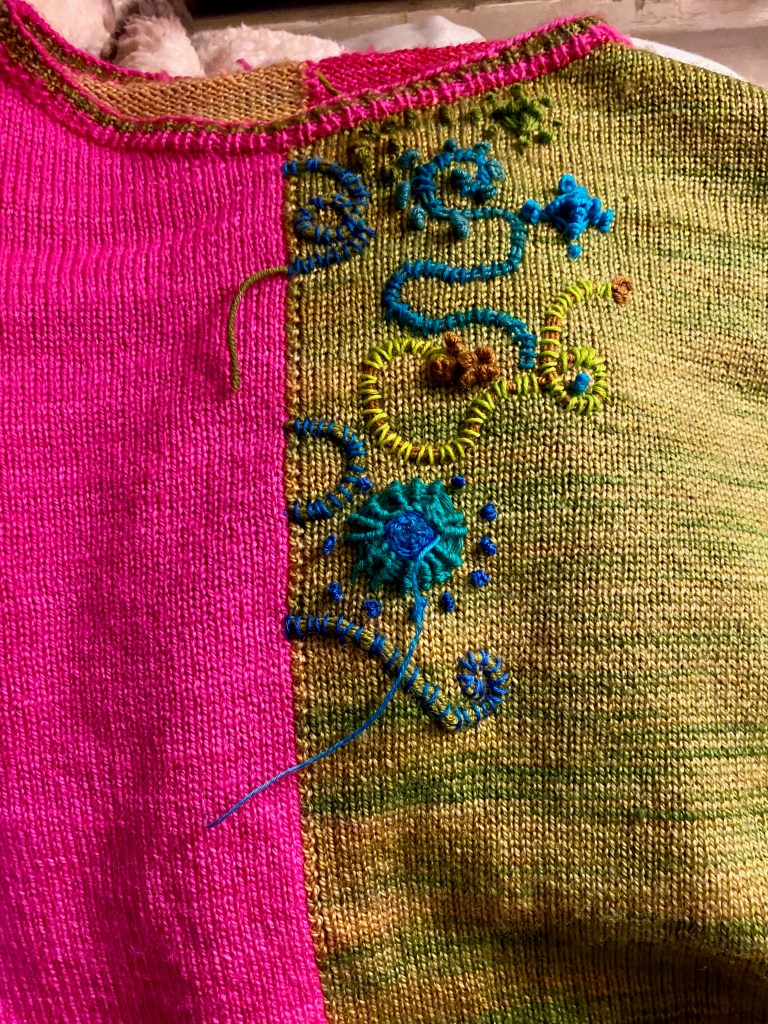 Blue and green embroidery on green side of paneled sweater