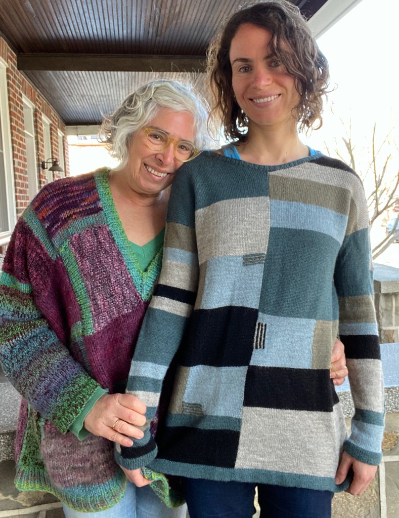 Mother-daughter sweaters of hand-knit patchwork pullover and machine-knit paneled pullover with intarsia and embroidery