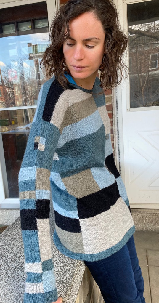 Side view of paneled machine-knit pullover showing intarsia detail on sleeve