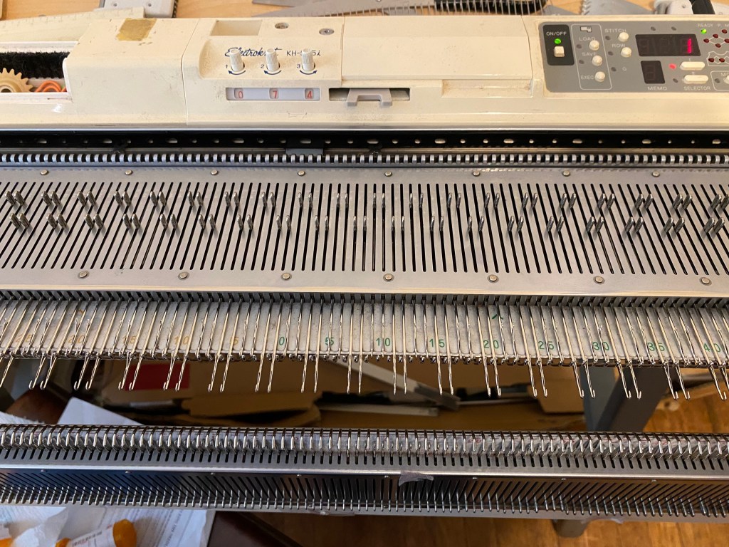 Preprogrammed machine knitting pattern with all needles in correct position after cleaning the needle selection apparatus