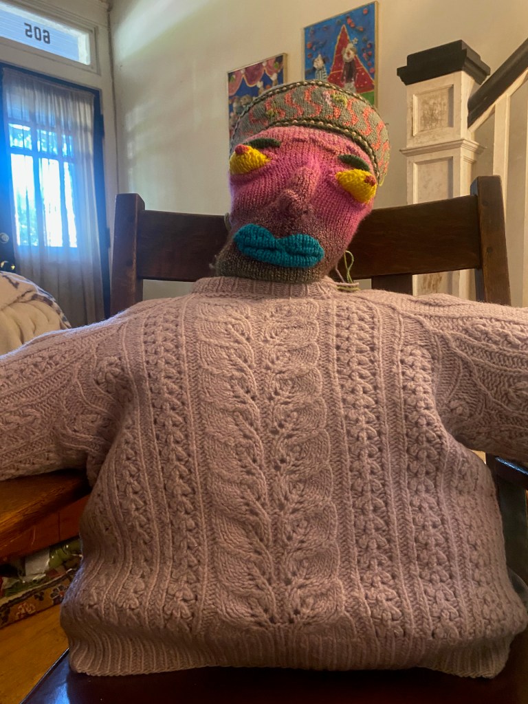Face stitched to hat and stuffed with fill for the head, head stitched to neck of sweater, sweater filled with pillow and bolsters