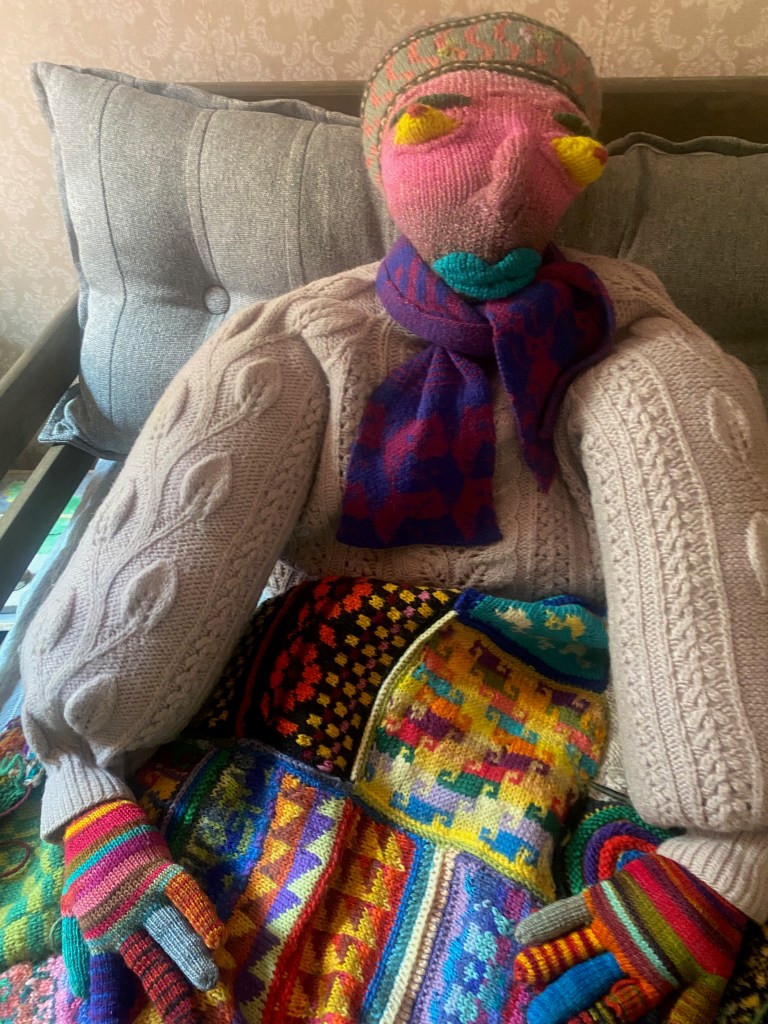 Assembled sweater pillow made of reclaimed sweater and knitted accessories, with patchwork blanket made of knitting swatches