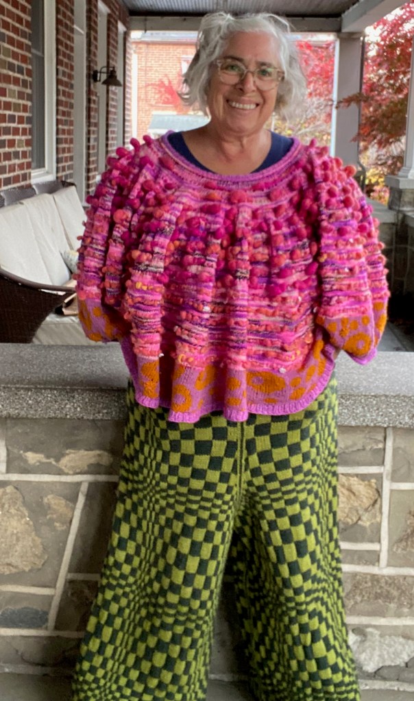 Op-art checkerboard pants paired with flowing sweater made of pink art yarn